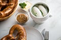 German WeiÃÅ¸wurst white sausage in porcelain pot, Bavarian sweet mustard, butter and pretzel on marble table